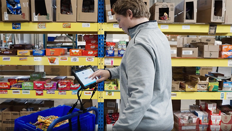 Worker uses tablet to pick products in a warehouse.